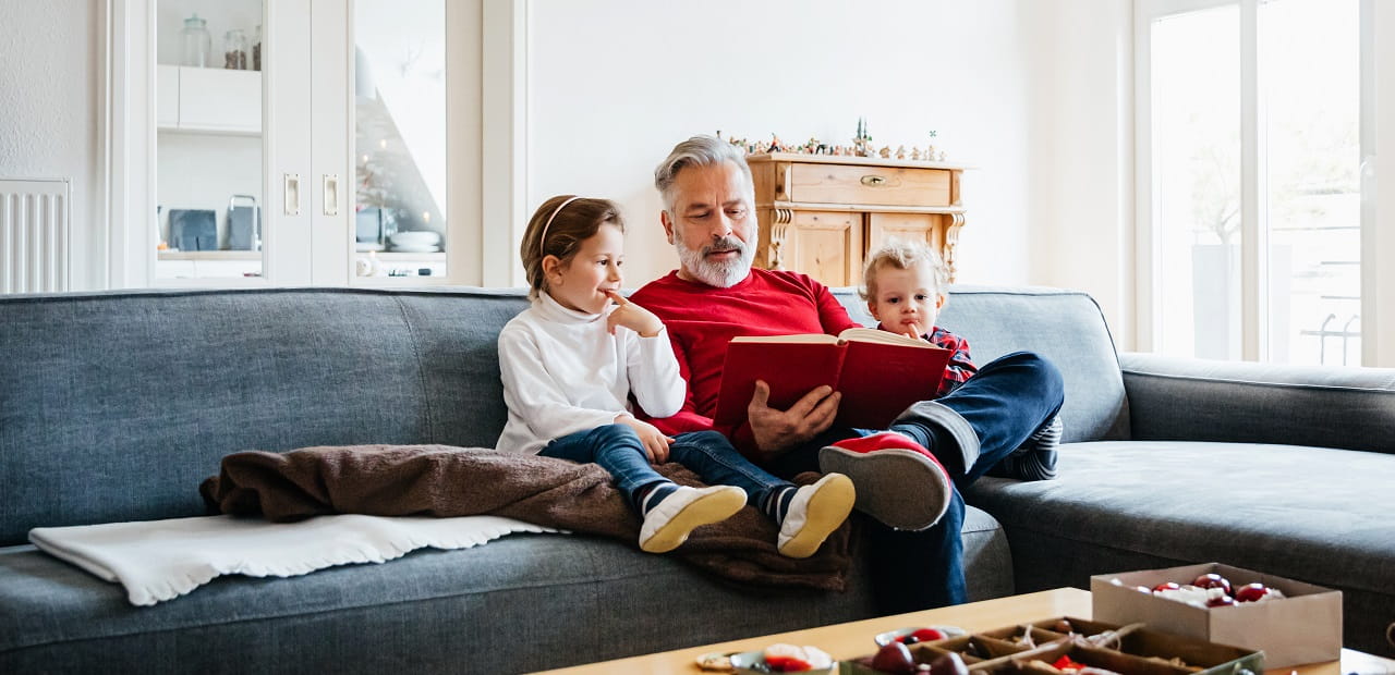 Man sits on the couch with his grandchildren. 