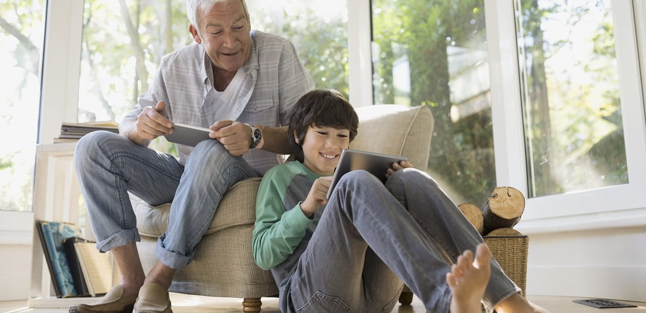 Grandfather and grandson using technology in living room