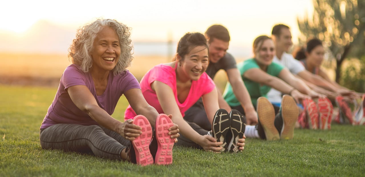 A row of smiling individuals stretching as part of their workout